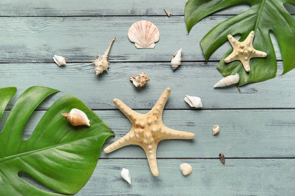 Композиція з пальмовим листям, морськими зірками і черепашками на кольоровому дерев'яному фоні
 - Фото, зображення