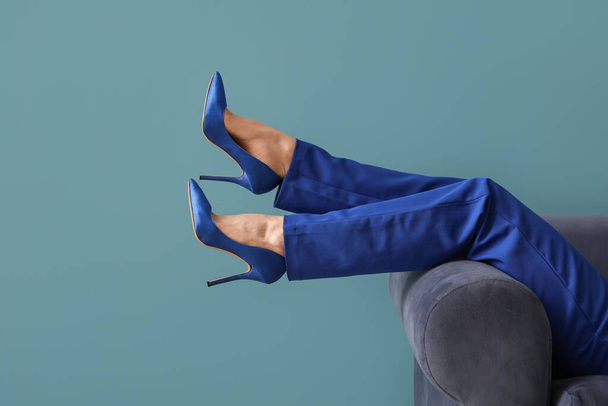 Female legs in high heels on sofa against blue background - Photo, Image