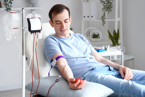 Νεαρός με μπάλα λαβής που δωρίζει αίμα στην κλινική - Φωτογραφία, εικόνα
