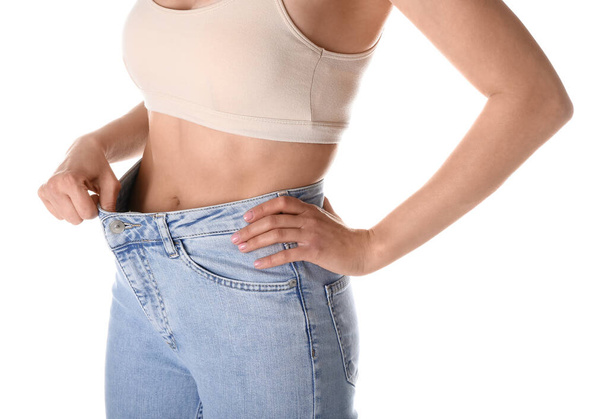 Young woman in loose jeans on white background. Diet concept - Foto, afbeelding
