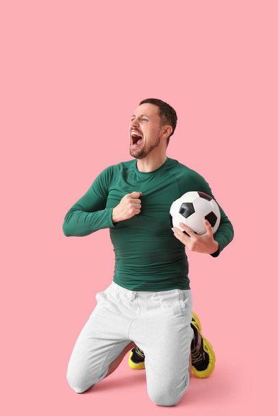 Hombre gritando con pelota de fútbol sobre fondo rosa - Foto, imagen