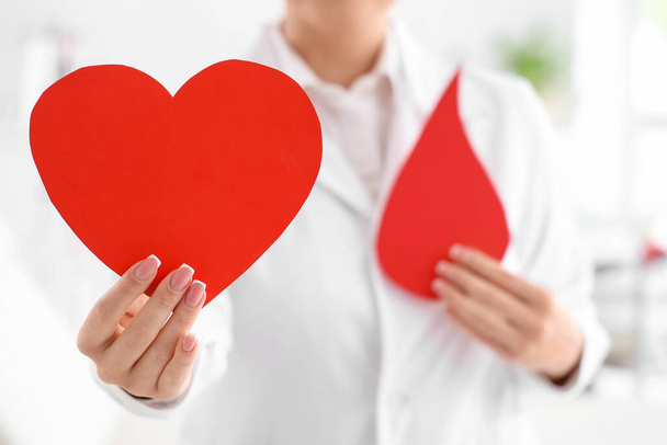 Médecin femme avec coeur en papier et goutte de sang à la clinique, gros plan - Photo, image