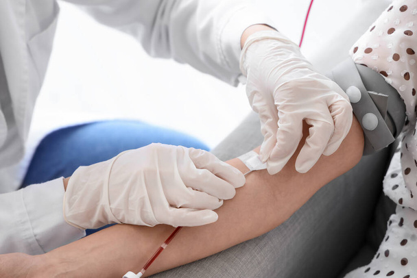 Female doctor taking young donor's blood in clinic, closeup - Photo, Image