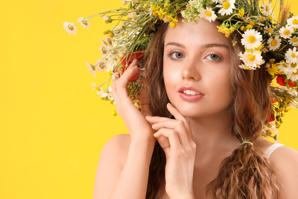 Beautiful young woman in flower wreath on yellow background. Summer solstice - Фото, изображение