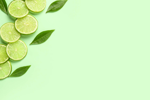 Scheiben frischer Limetten mit Blättern auf grünem Hintergrund - Foto, Bild