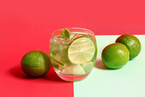 Glass of cold mojito and lime on colorful background - Fotó, kép