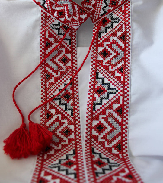 Fragment van Oekraïense zwarte en rode etnische borduursels op de kraag van een wit vyshyvanka shirt - Foto, afbeelding