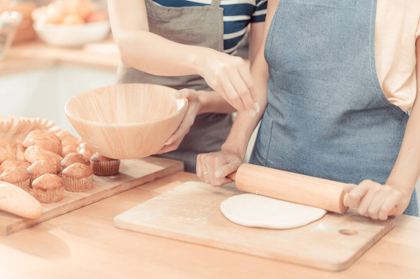 de hand van de vrouw is bloem verversen om de pasta op de houten tafel te maken, in concept van Italiaans eten. dorsen bloem voor het maken van brood bakkerij in gezellige keuken thuis. - Foto, afbeelding
