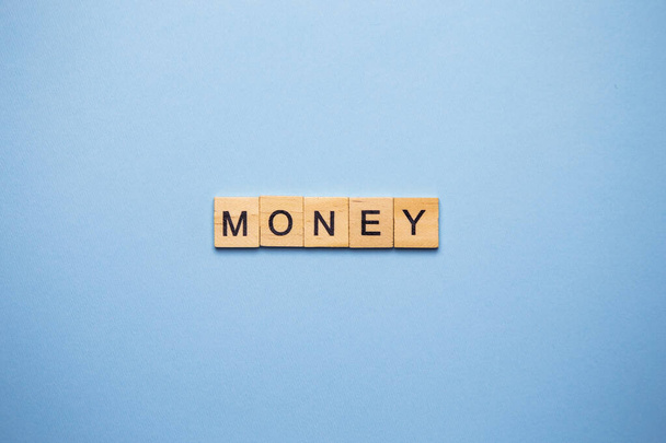 Οικονομική έννοια. Σε μια μπλε επιφάνεια, ξύλινα κυβάκια με τα χρήματα επιγραφή - Φωτογραφία, εικόνα