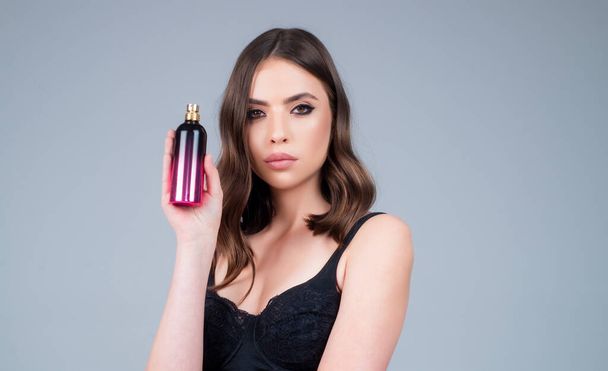 Perfume bottle. Woman with spray aroma perfume. Woman holding a perfumes bottle. Beautiful girl using perfume. Woman with bottle of perfume. Woman presents perfumes fragrance - Foto, imagen