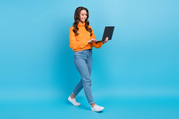 Full length photo of sweet shiny lady dressed orange pullover communicating modern device isolated blue color background. - Fotó, kép