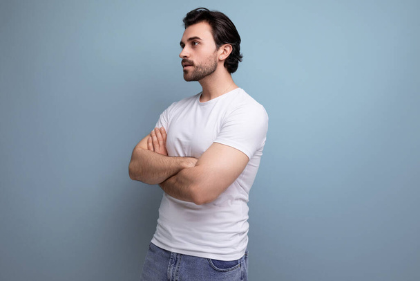 retrato de un hombre barbudo en una camiseta blanca con una apariencia de modelo en un fondo de estudio con espacio para copiar. - Foto, Imagen