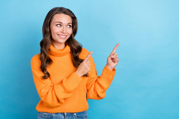 Photo of cute dreamy woman dressed orange sweater looking showing two fingers empty space isolated blue color background. - Photo, image
