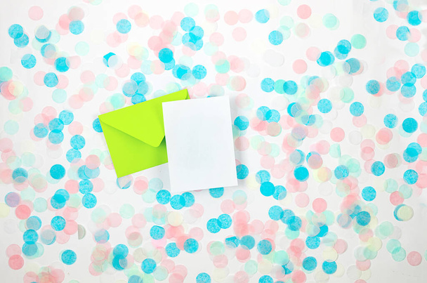 Green envelope with blank card and colorful paper confetti on white background with copyspace in greeting card and party invitation template design for Christmas wedding Mother day or birthday - Photo, Image