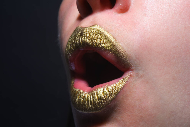 Gold lips, golden lipgloss on sexy lips, metallic mouth. Beauty woman mouth. Sexy girl golden lips, gold mouth. Glowing gold skin and gild lips. Surprised mouth - Zdjęcie, obraz