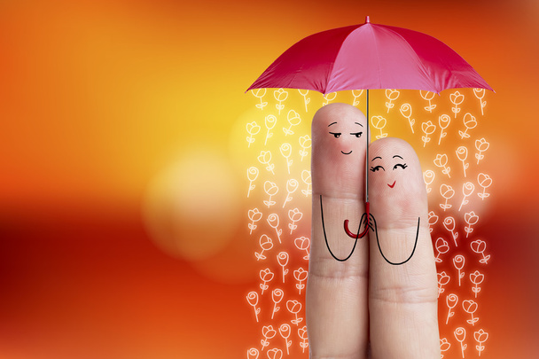 Conceptual finger art. Lovers is embracing and holding red umbrella with falling flowers. Stock Image - Photo, Image