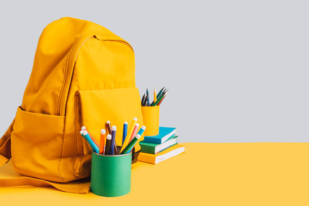 School supplies with books and backpack on yellow background. - Photo, Image