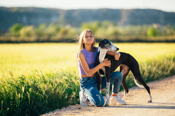 Portrait of a beautiful young blond woman with her greyhound dog. - Photo, Image