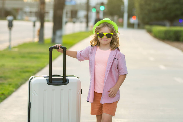 Funny child traveller. Little traveler tourist boy 7-8 years old. Traveling abroad to travel on weekends getaway. Independent kid boy travelling with big travel bag - Foto, afbeelding