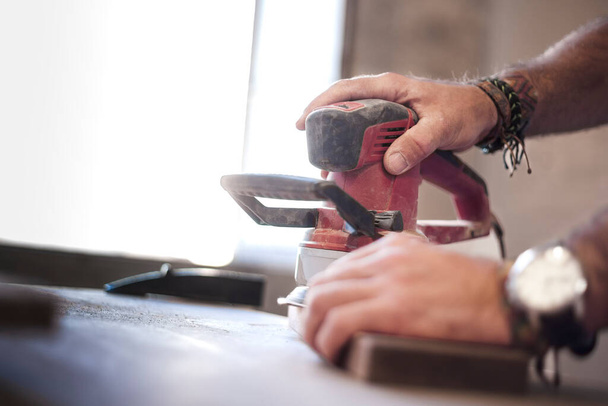 Dynamic shot capturing the artistry of a woodworker's hands polishing wood with a random orbital sander. The composition includes ample copy space for personalized text or branding elements. - Photo, Image