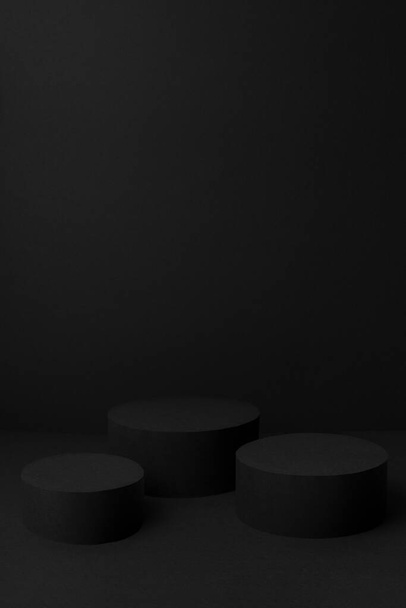 Abstract black stage with three cylinder podiums mockup for presentation cosmetic products, goods, advertising, design, text with soft gradient, in trendy exquisite simple style, vertical, copy space. - Foto, immagini