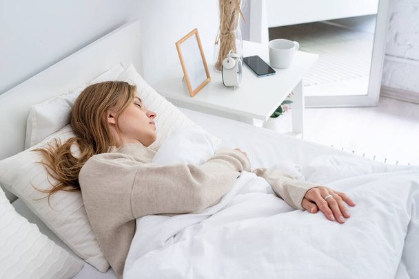 Mujer caucásica durmiendo en la cama en casa. joven mujer milenaria durmiendo, luz de la mañana en la cama - Foto, Imagen