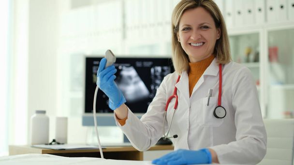Usmívající se doktorka drží ultrazvukovou sondu v rukou na klinice. Diagnóza vnitřních onemocnění v medicíně koncept - Fotografie, Obrázek