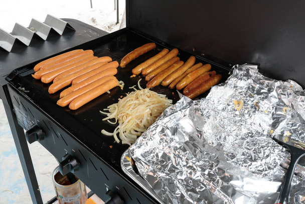 A traditional australian bbq sausage sizzle, sausages cooking on a barbeque - Zdjęcie, obraz