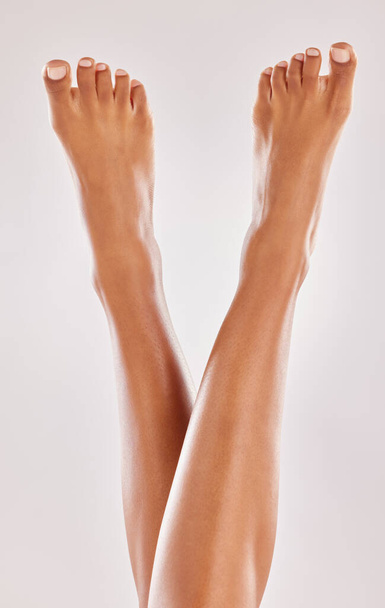 Woman, legs and feet with beauty and skin, hair removal and pedicure isolated on studio background. Body, skincare and female model with dermatology and grooming, epilation and cosmetic treatment. - 写真・画像