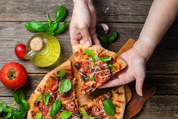 食欲をそそるピザ。木の背景にハム、キノコ、トマトのピザ - 写真・画像