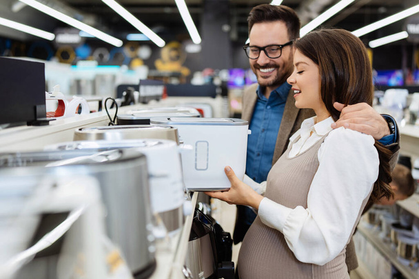 Beautiful and happy middle age couple buying consumer tech products in modern home tech store. They are choosing small kitchen appliances. People and consumerism concept. - Foto, immagini