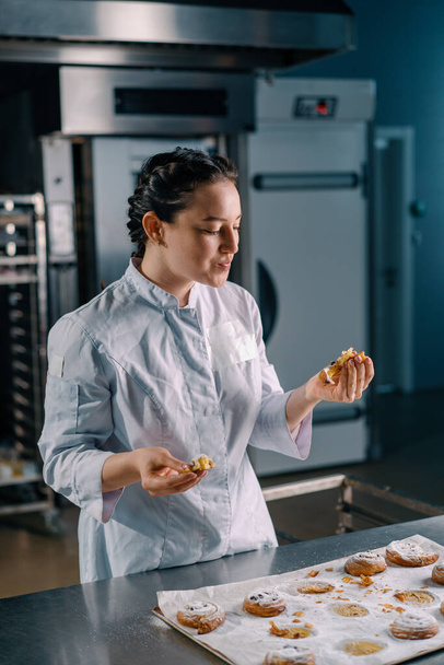 piękna kobieta piekarz łzy gotowy świeżo pieczone gorące aromatyczne bułki sprawdza ciasta produkcji piekarni - Zdjęcie, obraz