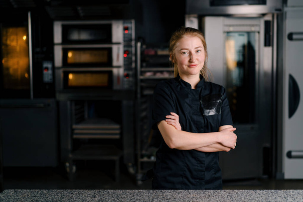un beau pâtissier professionnel dans un uniforme se tient sur le lieu de travail avant de commencer à travailler dans la cuisine professionnelle - Photo, image
