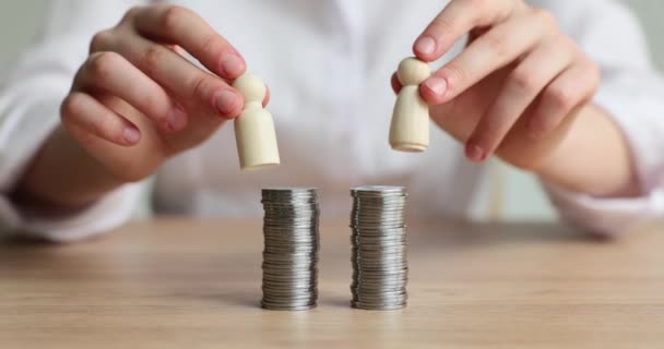 Žena klade dřevěné figurky na stříbrné mince na dřevěný stůl. Rovný přístup k peněžním prostředkům pro koncepci zpomaleného pohybu obchodních partnerů - Záběry, video