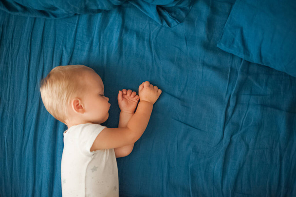 Toddler sleeps close-up on bed with blue plaid. - Φωτογραφία, εικόνα