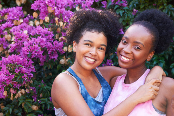 Dos mejores amigos abrazando y posando al aire libre en verano, flores rosadas amistad. Foto de alta calidad - Foto, imagen