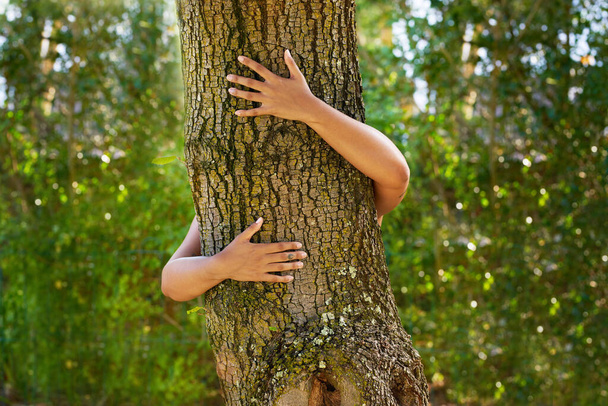 Black woman hugging a tree trunk in forest. Concept of care for environment. High quality photo - Φωτογραφία, εικόνα