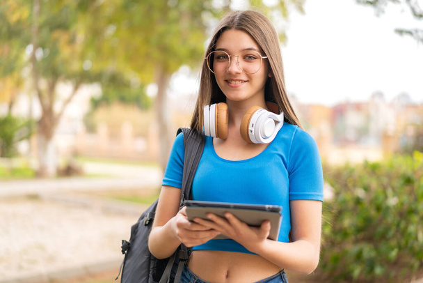 Nastolatka na świeżym powietrzu trzymająca tabletkę - Zdjęcie, obraz