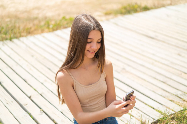 Девушка на улице, отправляя сообщение или электронную почту с мобильного телефона - Фото, изображение