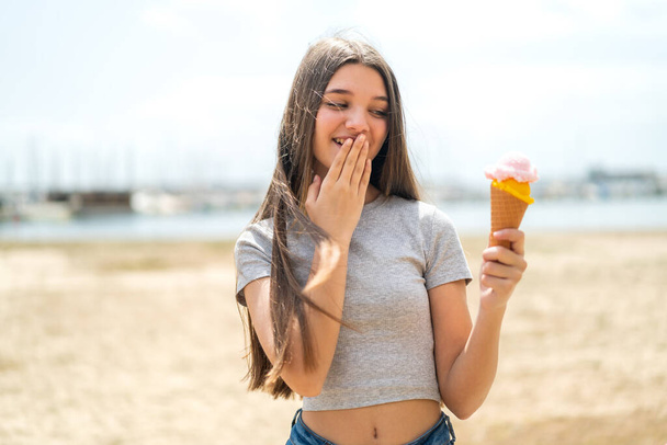 Ragazza adolescente con un gelato alla cornetta all'aperto con sorpresa e espressione facciale scioccata - Foto, immagini