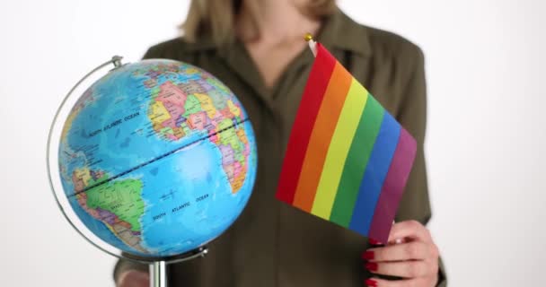 La mujer sostiene la bandera del mundo y el orgullo LGBT sobre un fondo blanco. Los homosexuales y transexuales en todo el mundo apoyan el rendimiento. Promoción de capital - Metraje, vídeo