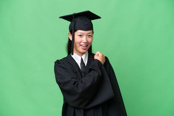 Young university graduate Asian woman over isolated background celebrating a victory - Foto, Imagem