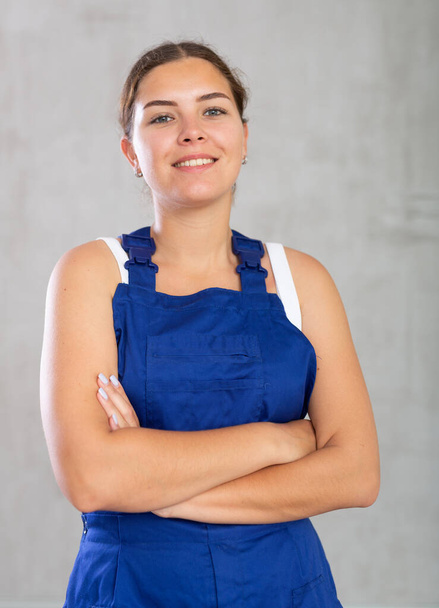 Young positive woman in work overalls posing against studio background.. - Foto, Bild