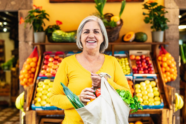 Mujer mayor feliz comprando frutas y verduras en el mercado - Concepto de compra de alimentos - Foto, imagen