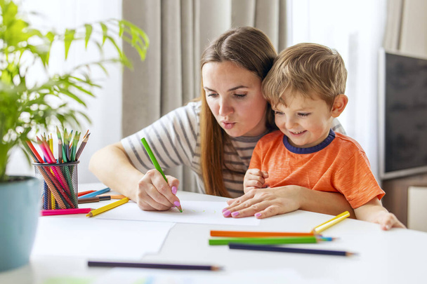 Mother and child drawing with pencils sitting at the desk at home. Happy family - Fotoğraf, Görsel