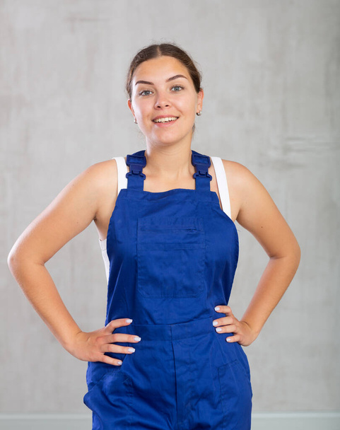 Cheerful female worker in overalls standing proudly and smiling - Foto, afbeelding