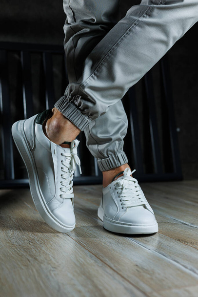 Men's summer shoes. Close-up of male legs in white leather sneakers. Collection of men's leather shoes - Foto, Imagem