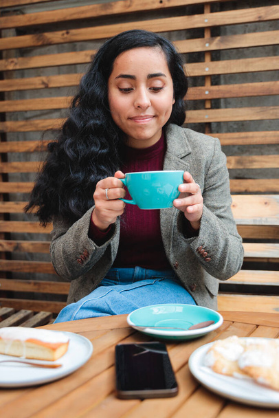 Taste of Serenity: Close-Up Shot of a Latina Woman Enjoying a Scrumptious Coffee at the Outdoor Patio of a Cozy Cafe. High quality photo - Foto, Imagen