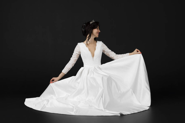 Όμορφη νύφη με κομψό εξαίσιο λευκό φόρεμα. απομονωμένο σε μαύρο φόντο. - Φωτογραφία, εικόνα