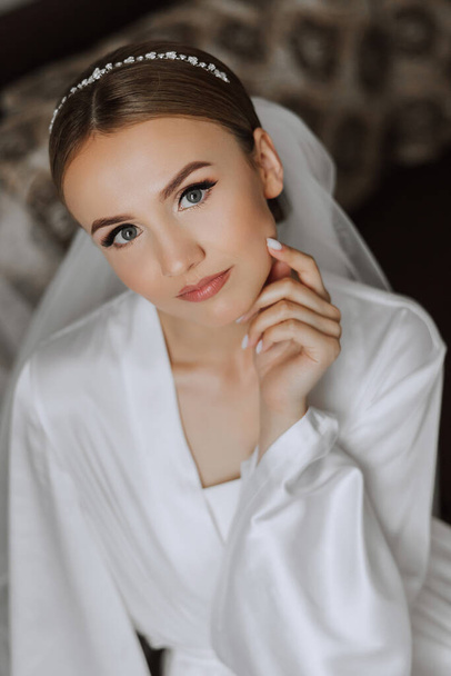 Morning of bride before the wedding. Beautiful young woman with long veil in a white robe. Natural beauty and professional make-up.Girl in white lace boudoir dress. - Fotografie, Obrázek